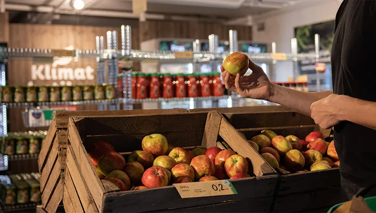 man picking an apple from a display at a store